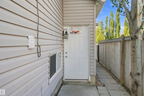 Rear entry door with exterior wall lantern and a concrete patio - 1328 80 Street Sw, Edmonton, AB - Outdoor With Exterior