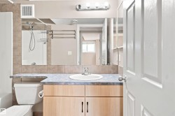 Bathroom featuring a light wood-finish vanity with a blue-hued countertop, an integrated sink, and a wall-mounted mirror - 