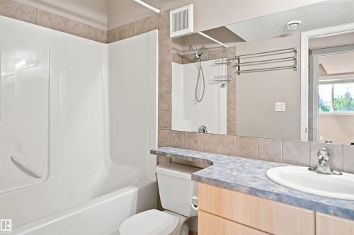 Bathroom featuring a vanity with an integrated sink, a tiled backsplash, and a large wall-mounted mirror - 1328 80 Street Sw, Edmonton, AB - Indoor Photo Showing Bathroom