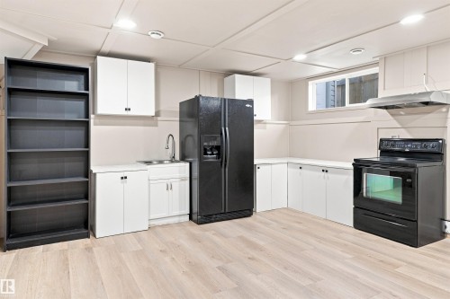 Kitchenette with light wood-finish flooring, white cabinetry, and stainless steel sink - 1328 80 Street Sw, Edmonton, AB - Indoor Photo Showing Kitchen