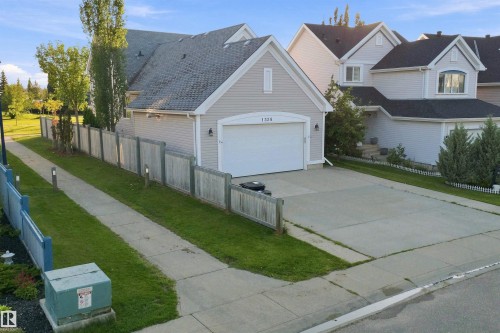 Property exterior featuring light siding, a dark roof, and an attached garage with a white door - 1328 80 Street Sw, Edmonton, AB - Outdoor