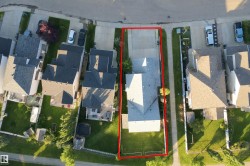Property with a distinct roofline, extensive driveway, and a spacious green lawn - 