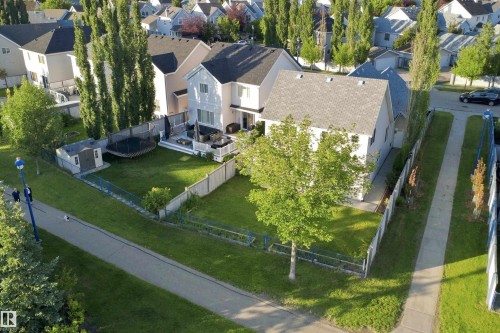 Spacious backyard featuring a large green lawn, a wooden privacy fence, and a patio area with a built-in deck - 1328 80 Street Sw, Edmonton, AB - Outdoor With View