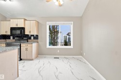 Kitchen featuring light wood-finish cabinetry, black appliance suite, dark blue subway tile backsplash, and light-colored countertops - 