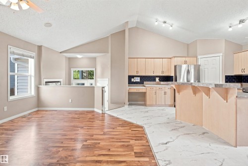 Open-concept living area featuring vaulted ceilings and a dual-surface flooring design - 1328 80 Street Sw, Edmonton, AB - Indoor Photo Showing Kitchen