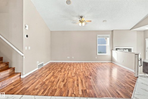 Spacious interior featuring wood-finish flooring, a contemporary ceiling fan, and a single window with horizontal blinds - 1328 80 Street Sw, Edmonton, AB - Indoor Photo Showing Other Room