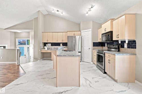 Kitchen featuring light wood-finish cabinetry, black subway tile backsplash, and light-toned countertops - 1328 80 Street Sw, Edmonton, AB - Indoor Photo Showing Kitchen