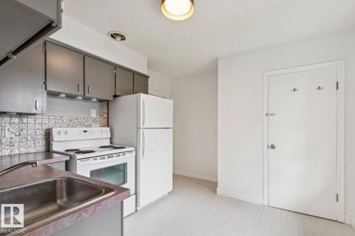 Kitchen featuring grey cabinetry, white electric range, white refrigerator, and a stainless steel sink - 8202 93A Avenue Nw, Edmonton, AB - Indoor Photo Showing Kitchen