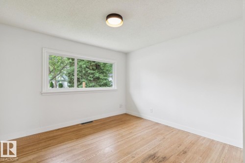 Bright interior space with wood-finish flooring, white walls, and a large window offering exterior views - 8202 93A Avenue Nw, Edmonton, AB - Indoor Photo Showing Other Room