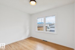 Light-filled interior space featuring wood-finish flooring, white walls, and a multi-pane window with white trim - 