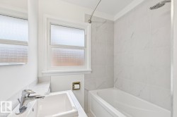 Bathroom featuring a single-handle chrome faucet, a white undermount sink, and a white bathtub with a curved shower rod - 