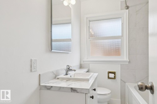 Compact bathroom featuring a white vanity with a marble-finish countertop and an integrated rectangular sink - 8202 93A Avenue Nw, Edmonton, AB - Indoor Photo Showing Bathroom