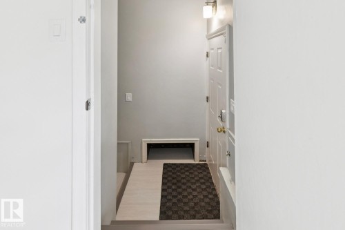 Entryway featuring a white paneled door with brass hardware, a contemporary wall sconce, and wood-finish flooring - 8202 93A Avenue Nw, Edmonton, AB - Indoor Photo Showing Other Room