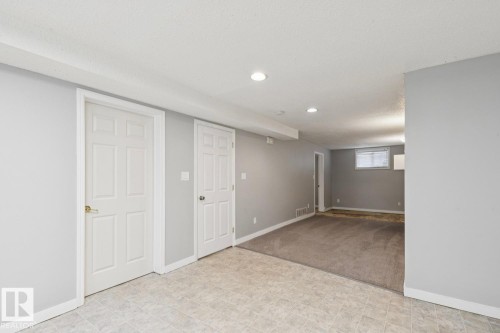 Finished lower-level space featuring light gray walls, white trim, and a combination of tile and carpet flooring - 8202 93A Avenue Nw, Edmonton, AB - Indoor Photo Showing Other Room