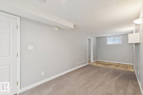 Spacious room featuring light gray walls, white baseboards, and a textured ceiling - 8202 93A Avenue Nw, Edmonton, AB - Indoor Photo Showing Other Room