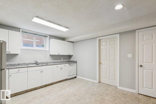 Kitchenette featuring white cabinetry, a double basin sink, dishwasher, and a refrigerator - 8202 93A Avenue Nw, Edmonton, AB - Indoor Photo Showing Kitchen With Double Sink