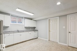 Kitchenette featuring white cabinetry, a double basin sink, dishwasher, and a refrigerator - 