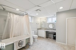 Bathroom featuring a classic clawfoot bathtub with shower, a vanity with single sink, and a drop ceiling with recessed lighting - 