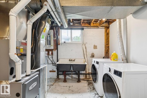 Laundry area featuring a dual-basin utility sink, contemporary washer and dryer, and a window providing natural light - 8202 93A Avenue Nw, Edmonton, AB - Indoor Photo Showing Laundry Room