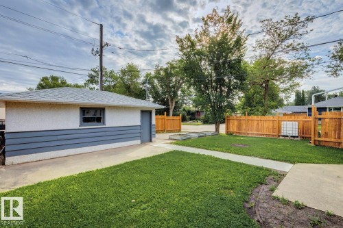 Detached garage with stucco and horizontal siding, featuring a gray shingled roof, a window, and a service door - 8202 93A Avenue Nw, Edmonton, AB - Outdoor