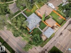Property featuring a main residence with a gray shingle roof, a detached garage with a brown shingle roof, and a fenced backyard with a patio area - 