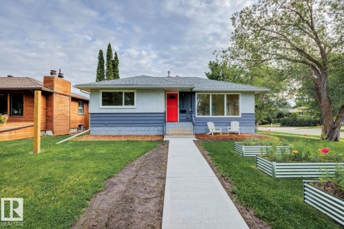 Charming bungalow exterior featuring a red entry door, light gray siding, and a contrasting blue lower facade - 8202 93A Avenue Nw, Edmonton, AB - Outdoor