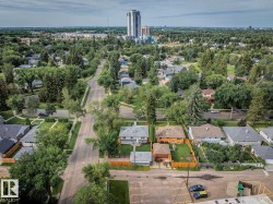 Elevated perspective showcasing residential properties with mature trees, a paved street, and surrounding greenery - 
