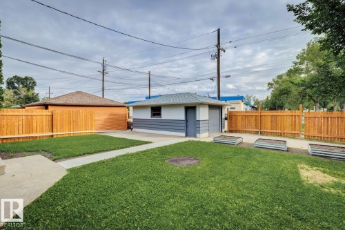 Detached garage featuring white and gray siding, accompanied by a separate garage structure with wood-finish siding and a shingled roof - 8202 93A Avenue Nw, Edmonton, AB - Outdoor