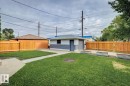 Detached garage featuring white and gray siding, accompanied by a separate garage structure with wood-finish siding and a shingled roof - 8202 93A Avenue Nw, Edmonton, AB  - Outdoor 