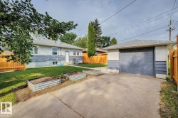 Detached garage with a gray overhead door, asphalt driveway, and a wooden privacy fence - 