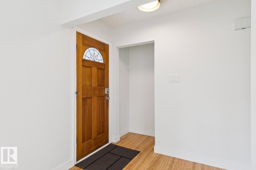 Warm wood-finish door with an arched decorative glass insert and polished hardware - 8202 93A Avenue Nw, Edmonton, AB - Indoor Photo Showing Other Room