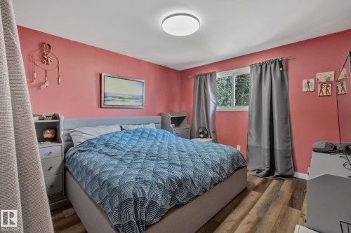 Interior room featuring wood-finish flooring, a flush-mount ceiling light fixture, and a window with dark drapery - 4723 105 Street Nw, Edmonton, AB - Indoor Photo Showing Bedroom
