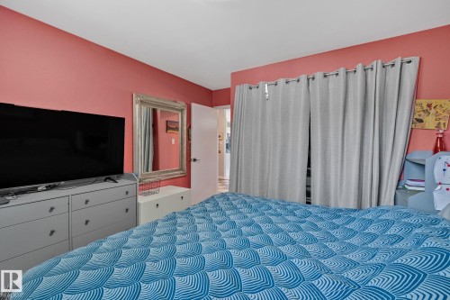 Interior room featuring red-painted walls, a built-in closet with privacy curtains, and a white interior door - 4723 105 Street Nw, Edmonton, AB - Indoor Photo Showing Bedroom