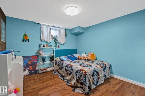 Bedroom featuring wood-finish flooring, light blue walls, and a recessed window - 4723 105 Street Nw, Edmonton, AB - Indoor Photo Showing Bedroom
