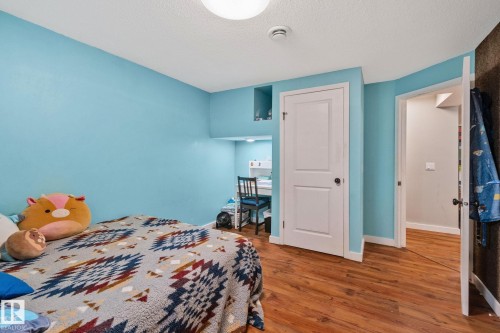 Room featuring wood-finish flooring, light blue walls, and a recessed desk area with built-in shelving - 4723 105 Street Nw, Edmonton, AB - Indoor Photo Showing Bedroom