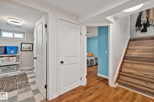 Wood-finish flooring throughout, complemented by a light wood-tone staircase with white risers - 4723 105 Street Nw, Edmonton, AB - Indoor Photo Showing Other Room