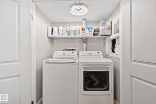 Dedicated laundry area featuring a washer and dryer, built-in shelving, and a ceiling-mounted light fixture - 4723 105 Street Nw, Edmonton, AB - Indoor Photo Showing Laundry Room