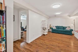 Spacious room featuring wood-finish flooring, white walls, and contemporary flush-mount lighting fixtures - 