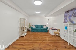 Spacious interior room featuring wood-finish flooring, white walls, and a recessed ceiling with flush-mount lighting fixtures - 