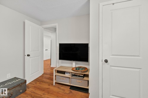 Interior room featuring wood-finish flooring, light-colored walls, and white paneled doors - 4723 105 Street Nw, Edmonton, AB - Indoor