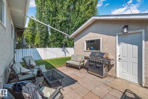 Paved patio area featuring a white privacy fence and a detached stucco structure - 4723 105 Street Nw, Edmonton, AB - Outdoor With Exterior