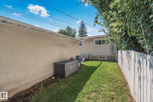 Expansive grassy yard with a weathered privacy fence and mature perimeter trees - 4723 105 Street Nw, Edmonton, AB - Outdoor