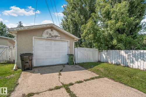 Detached garage featuring a paneled door, stucco exterior, and gable roofline - 4723 105 Street Nw, Edmonton, AB - Outdoor