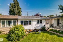 Front exterior featuring horizontal siding, a well-maintained lawn, multiple window units, and a paved walkway leading to the entrance - 