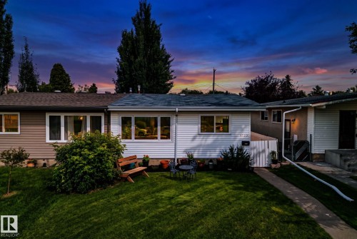 White siding exterior featuring multiple windows, a manicured front lawn, and a concrete walkway - 4723 105 Street Nw, Edmonton, AB - Outdoor
