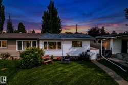White siding exterior featuring multiple windows, a manicured front lawn, and a concrete walkway - 