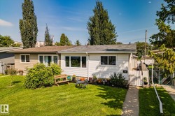 Front exterior featuring white horizontal siding, a gabled roofline, and a manicured front lawn - 