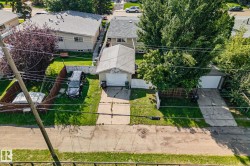 Aerial perspective showcasing two detached garage structures, each with a concrete driveway and surrounding green lawn - 