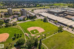 Expansive green space featuring a baseball diamond, walking paths, and mature trees - 
