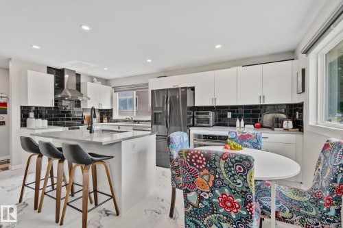 Kitchen featuring white cabinetry, black subway tile backsplash, and stainless steel appliances - 4723 105 Street Nw, Edmonton, AB - Indoor